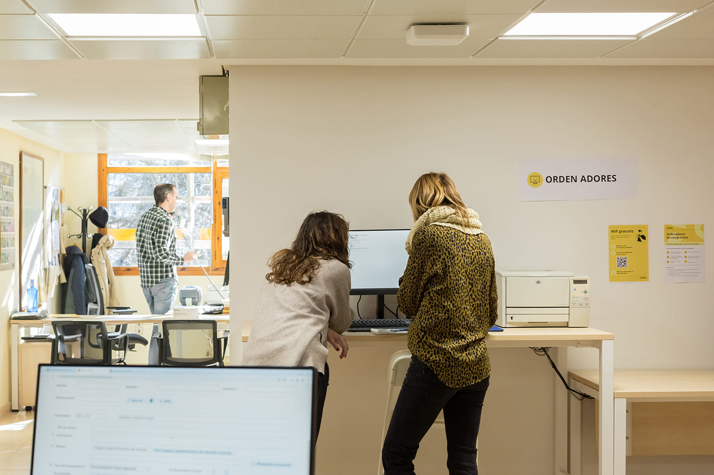 Dos personas consultan un ordenador en una oficina de atención a la ciudadanía